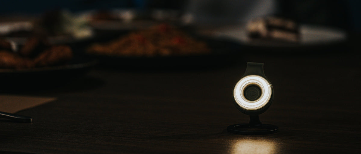 Scoutlite SparkO on its magnetic stand, lit, on a teal surface