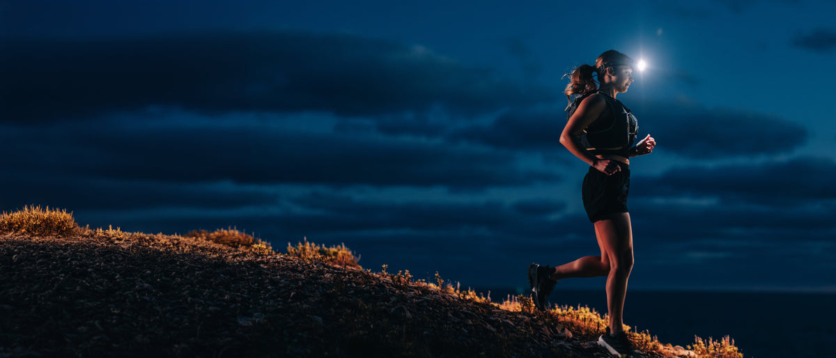 Trail runner on a coastal ridge at night with a Scoutlite headlamp beam