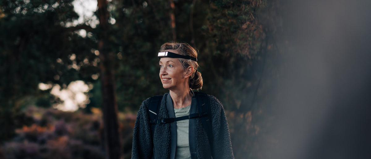 Two hikers in autumn woodland wearing lit Scoutlite headlamps