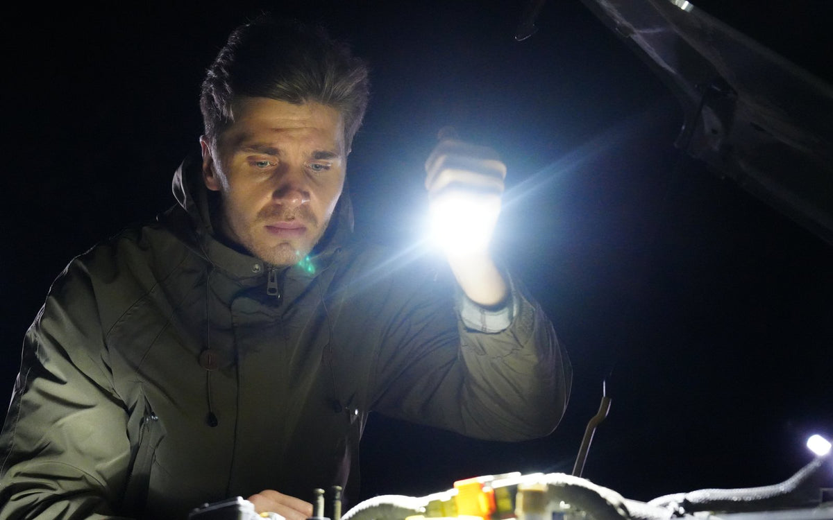 Man in a garage at night holding a lit Scoutlite Vario work light