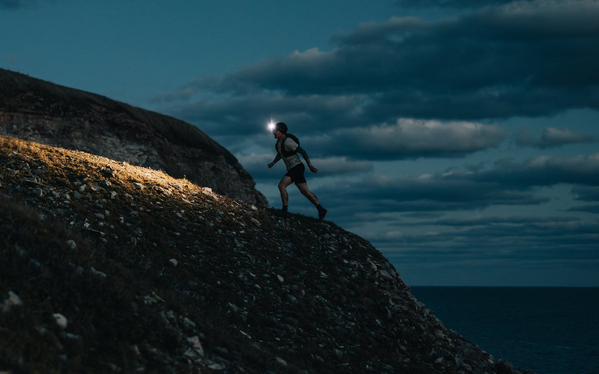 Runner on a night trail with a Scoutlite headlamp beam